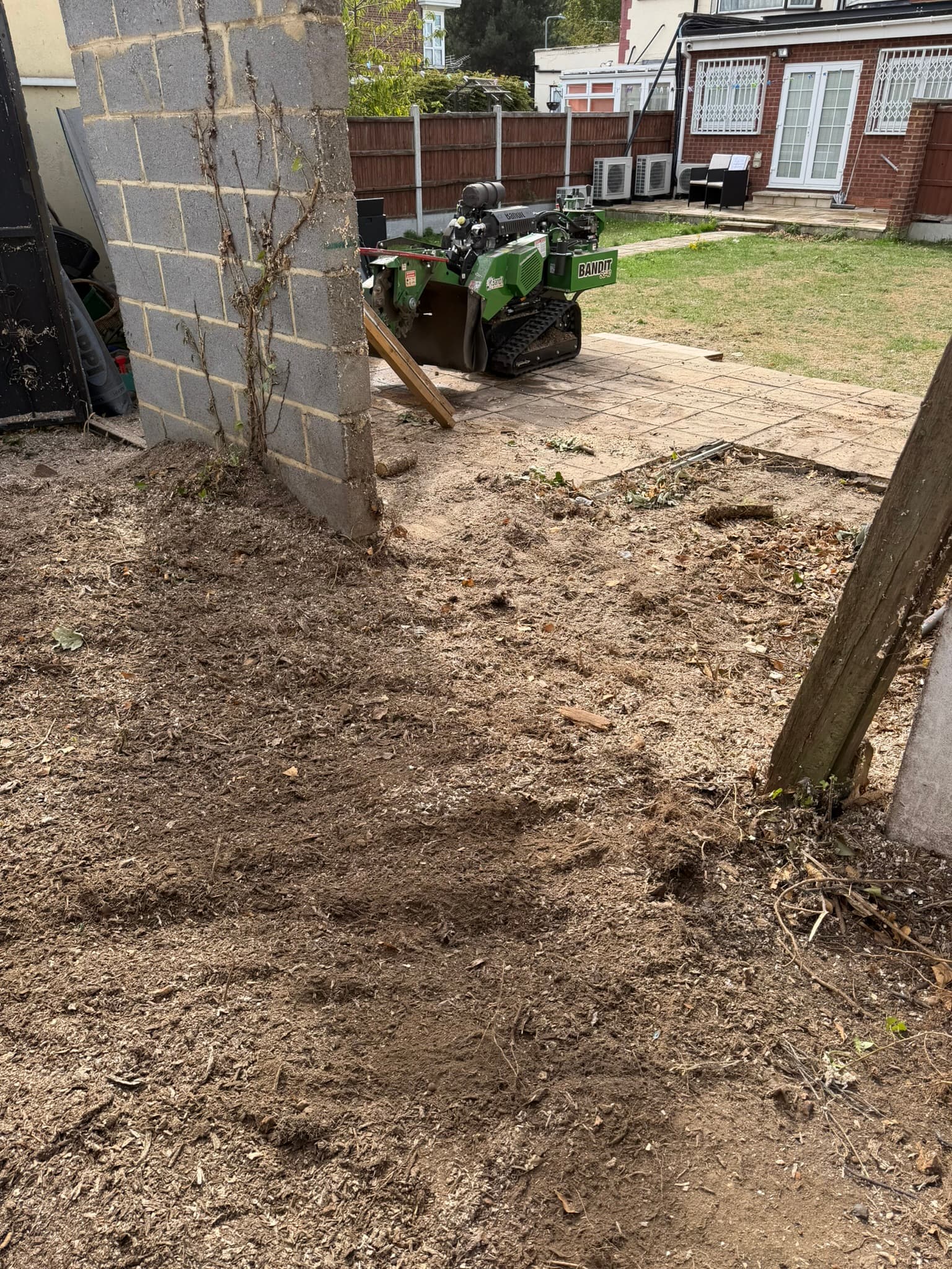 The cleared area covered in wood chippings after the sycamore stump was removed, with the Bandit SG-40 on the patio behind