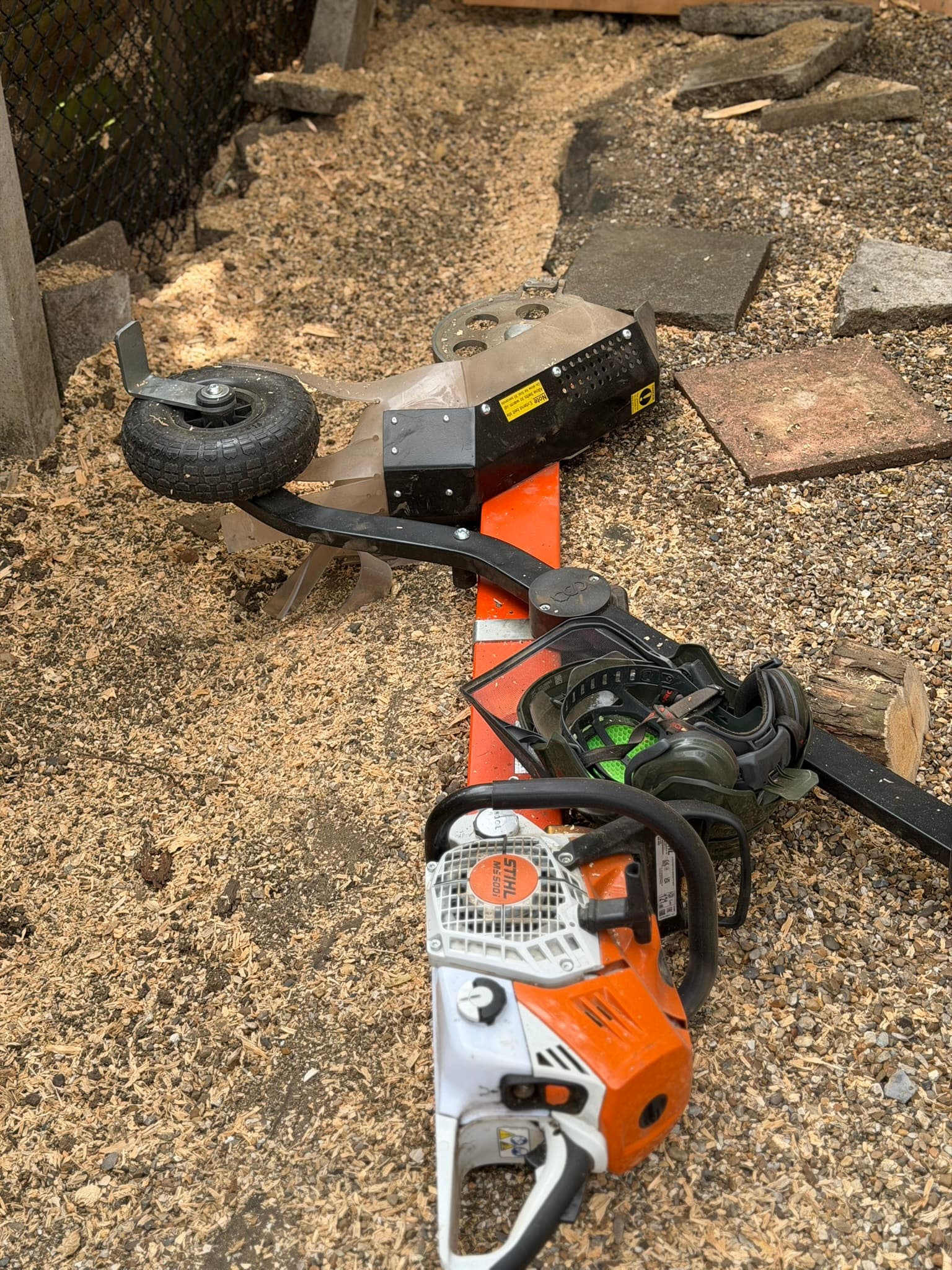 The Terminator chainsaw attachment beside a Stihl chainsaw and ear defenders, used for stumps the larger grinder could not reach