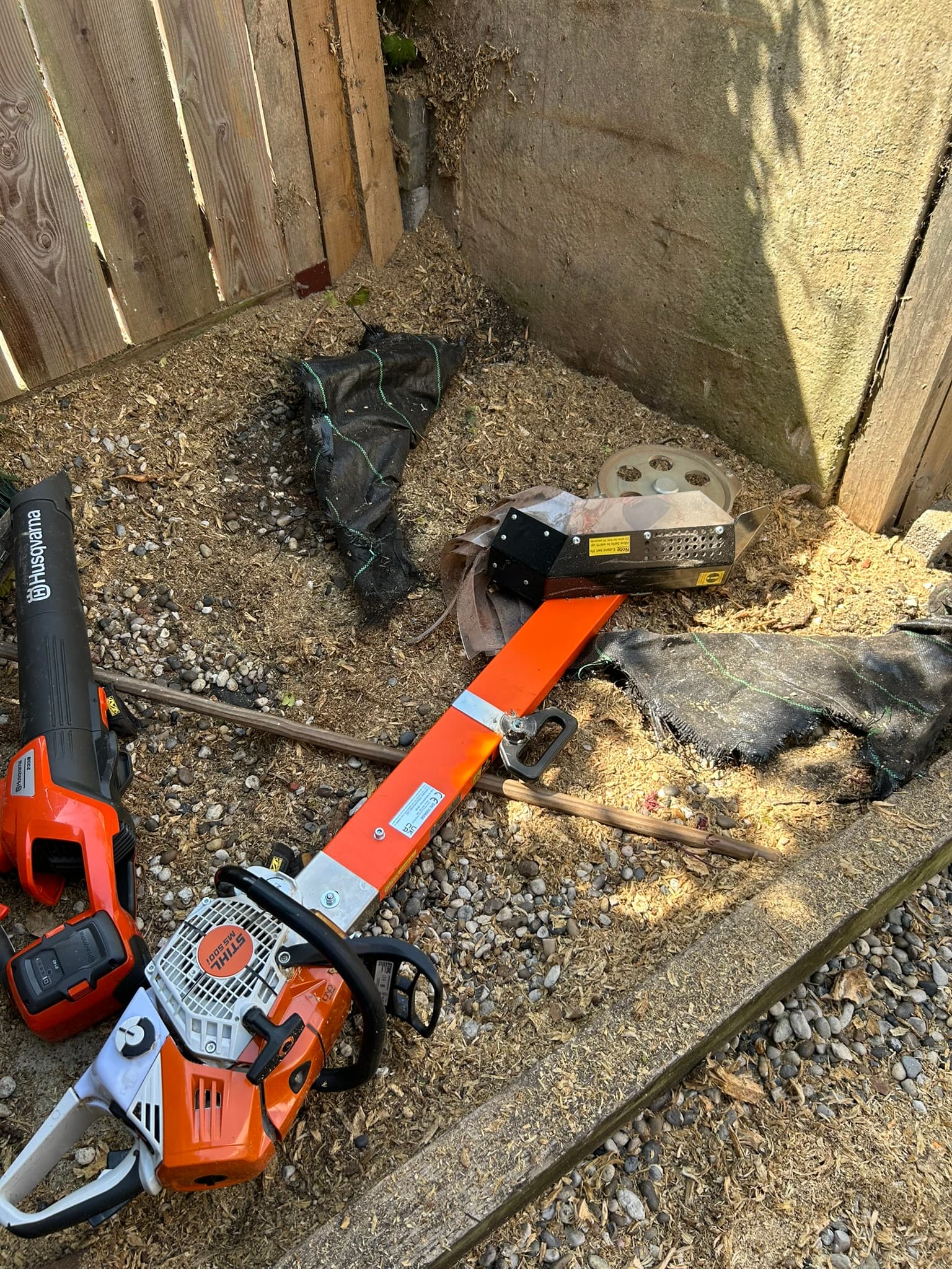 Stump being ground out, with fresh wood chippings building up against the fence