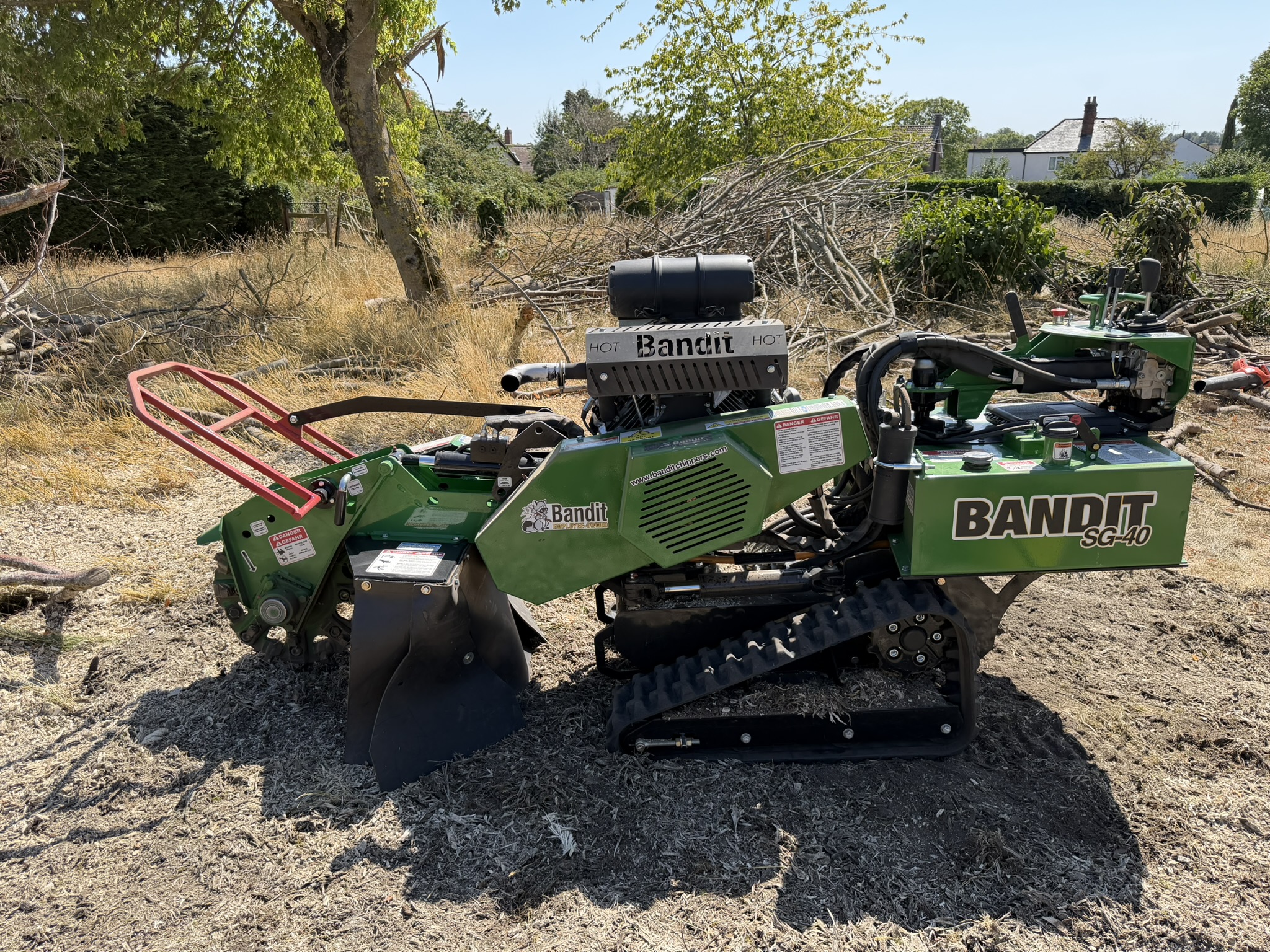 The Bandit SG-40 tracked stump grinder on a cleared, overgrown development plot in Chelmsford with brash piles and houses behind