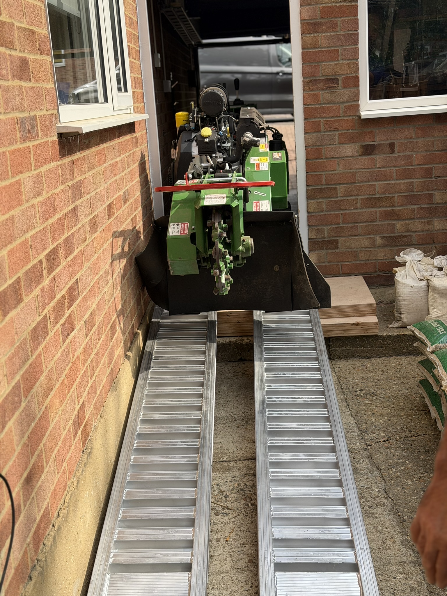 The Bandit SG-40 driven down aluminium ramps through a narrow gap between the house and a brick wall