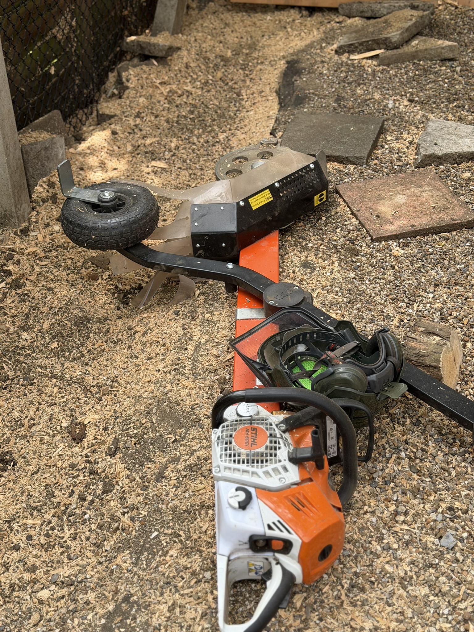 The Terminator chainsaw attachment beside a Stihl chainsaw and ear defenders, used for stumps the larger grinder could not reach