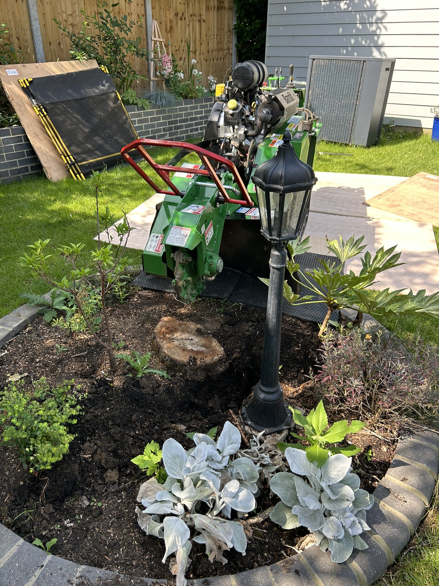 Stump grinder set up on protective mats over an ornamental flower bed, ready to start