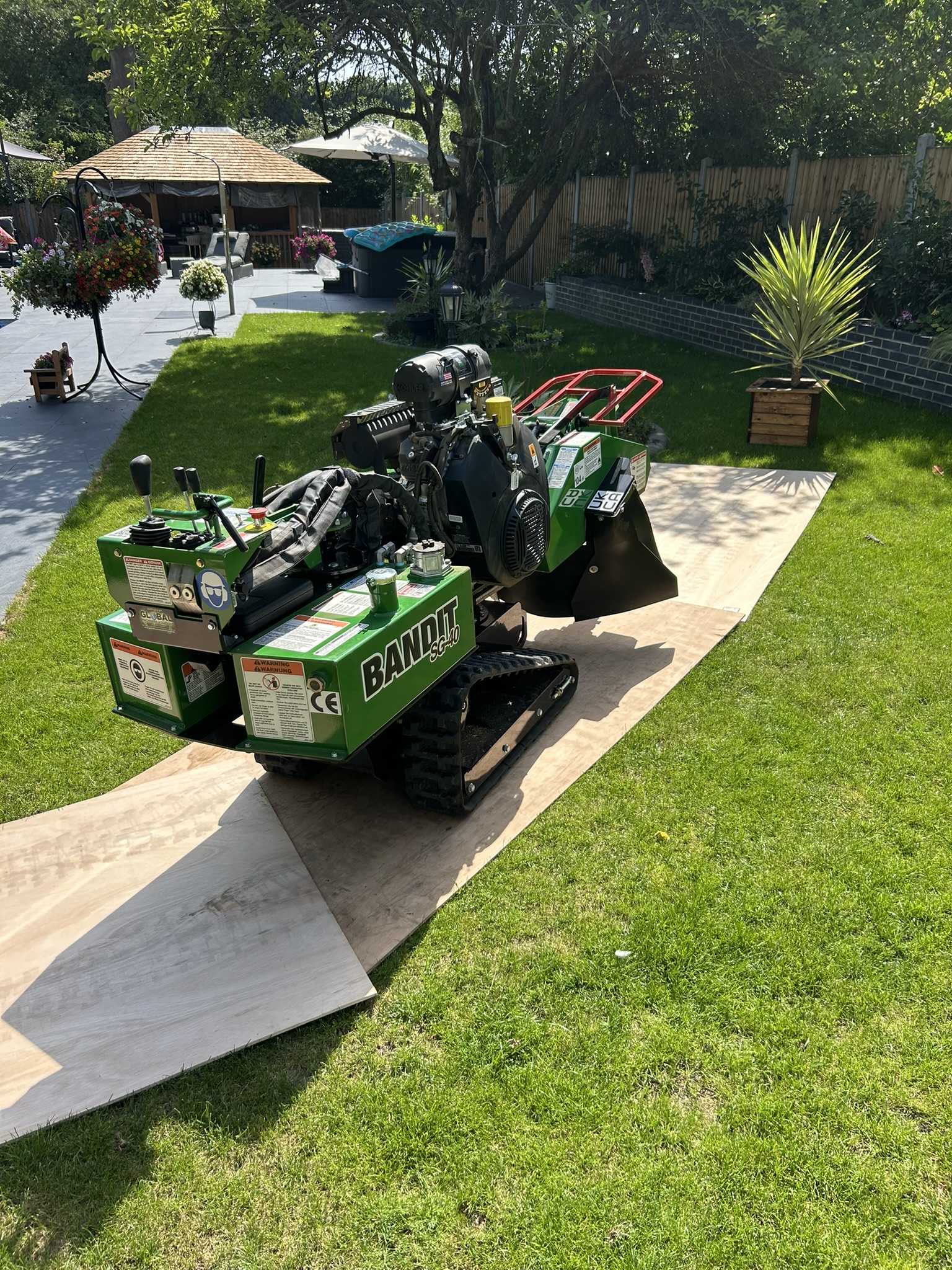 The tracked stump grinder driven across the lawn on plywood boards to protect the grass